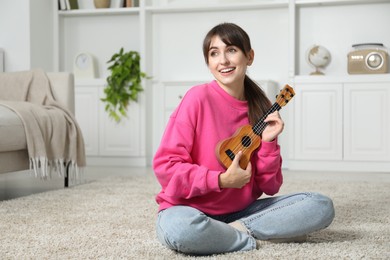 Photo of Happy woman playing ukulele on floor at home