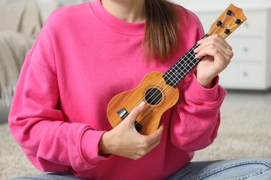 Photo of Woman playing ukulele at home, closeup view