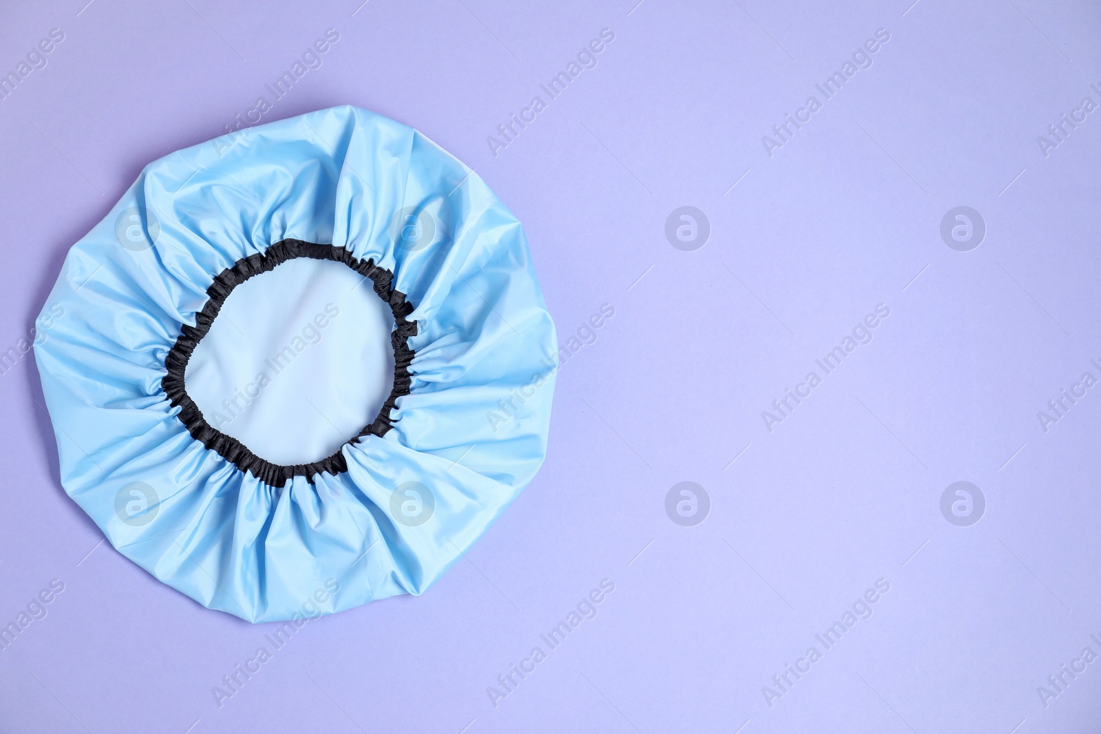 Photo of One shower cap on lilac background, top view. Space for text