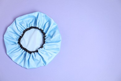 Photo of One shower cap on lilac background, top view. Space for text