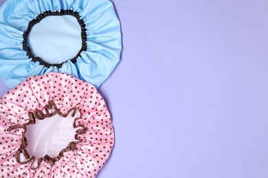 Photo of Two shower caps on lilac background, top view. Space for text