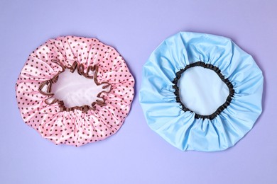 Photo of Two shower caps on lilac background, top view