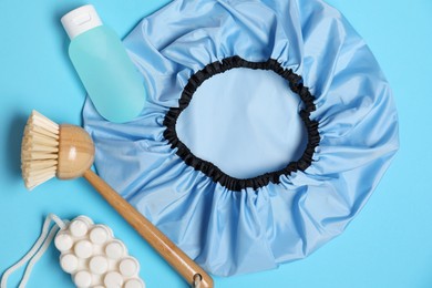 Photo of Shower cap and bath accessories on light blue background, flat lay