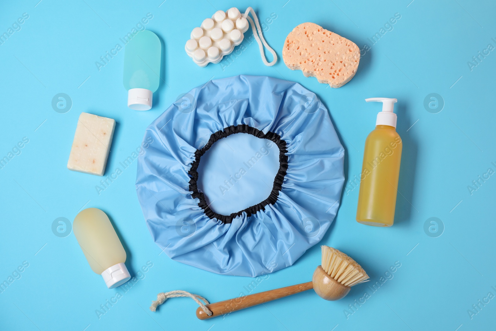 Photo of Shower cap and bath accessories on light blue background, flat lay