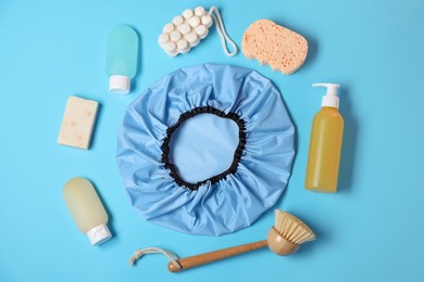 Photo of Shower cap and bath accessories on light blue background, flat lay