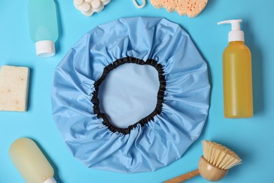 Photo of Shower cap and bath accessories on light blue background, flat lay