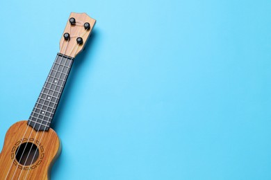 Photo of One ukulele on light blue background, top view. Space for text