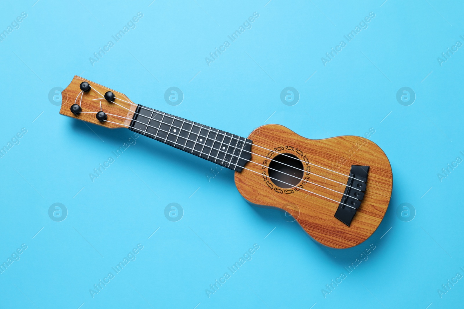 Photo of One ukulele on light blue background, top view