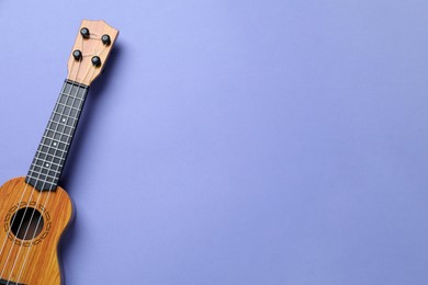 Photo of One ukulele on violet background, top view. Space for text