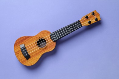 Photo of One ukulele on violet background, top view