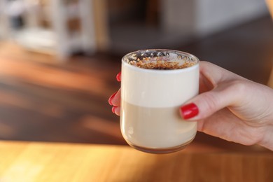 Photo of Woman with glass of aromatic coffee in cafe, closeup. Space for text