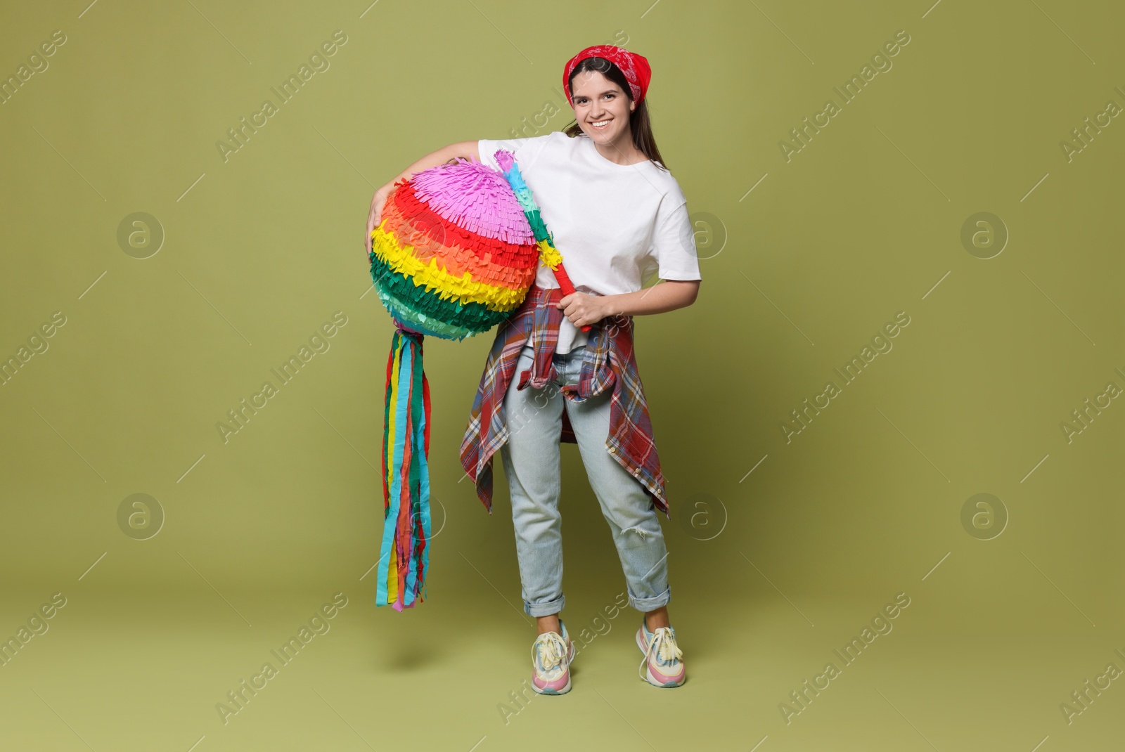 Photo of Happy woman with colorful pinata and stick on green background