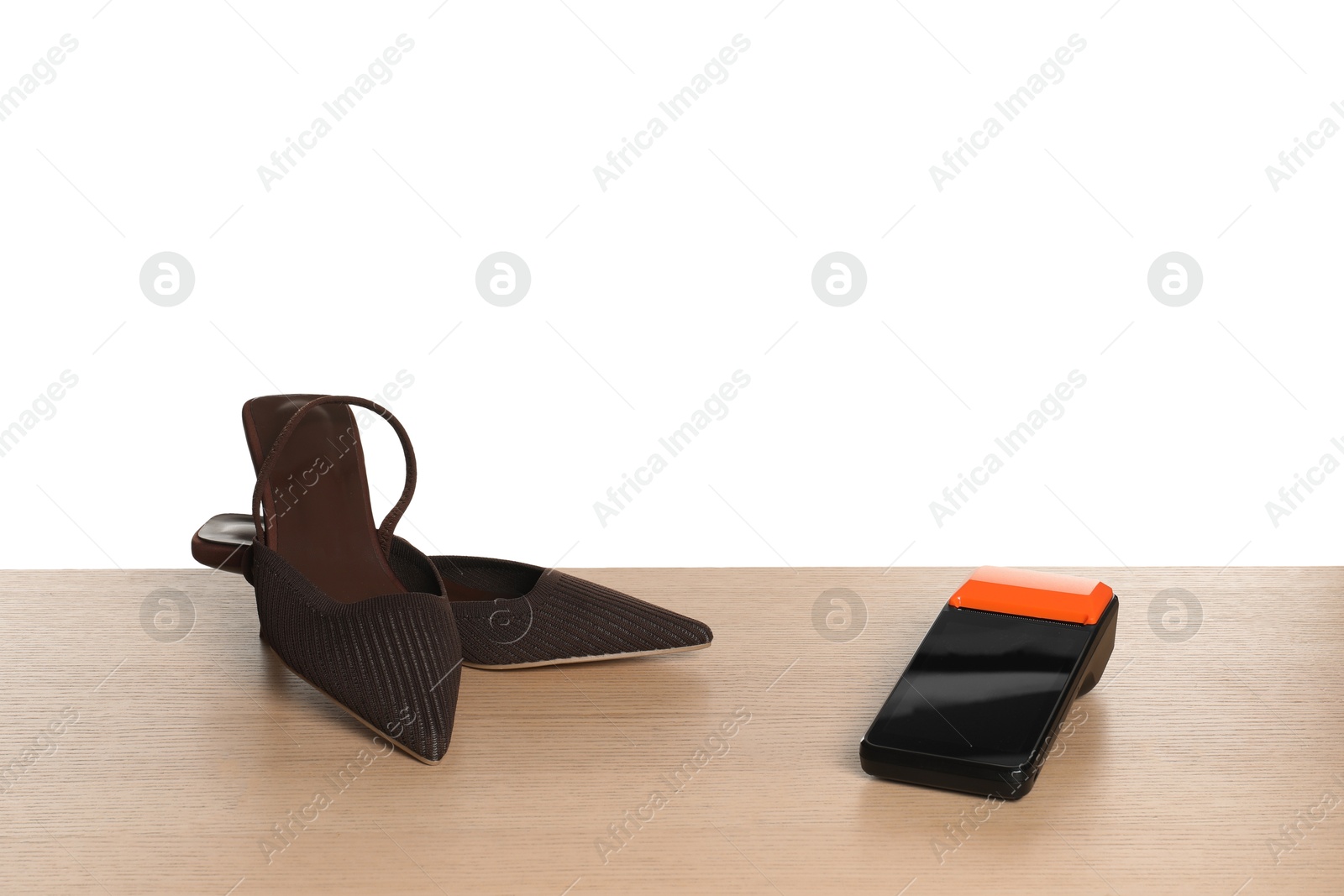 Photo of Payment terminal and shoes on wooden table against white background