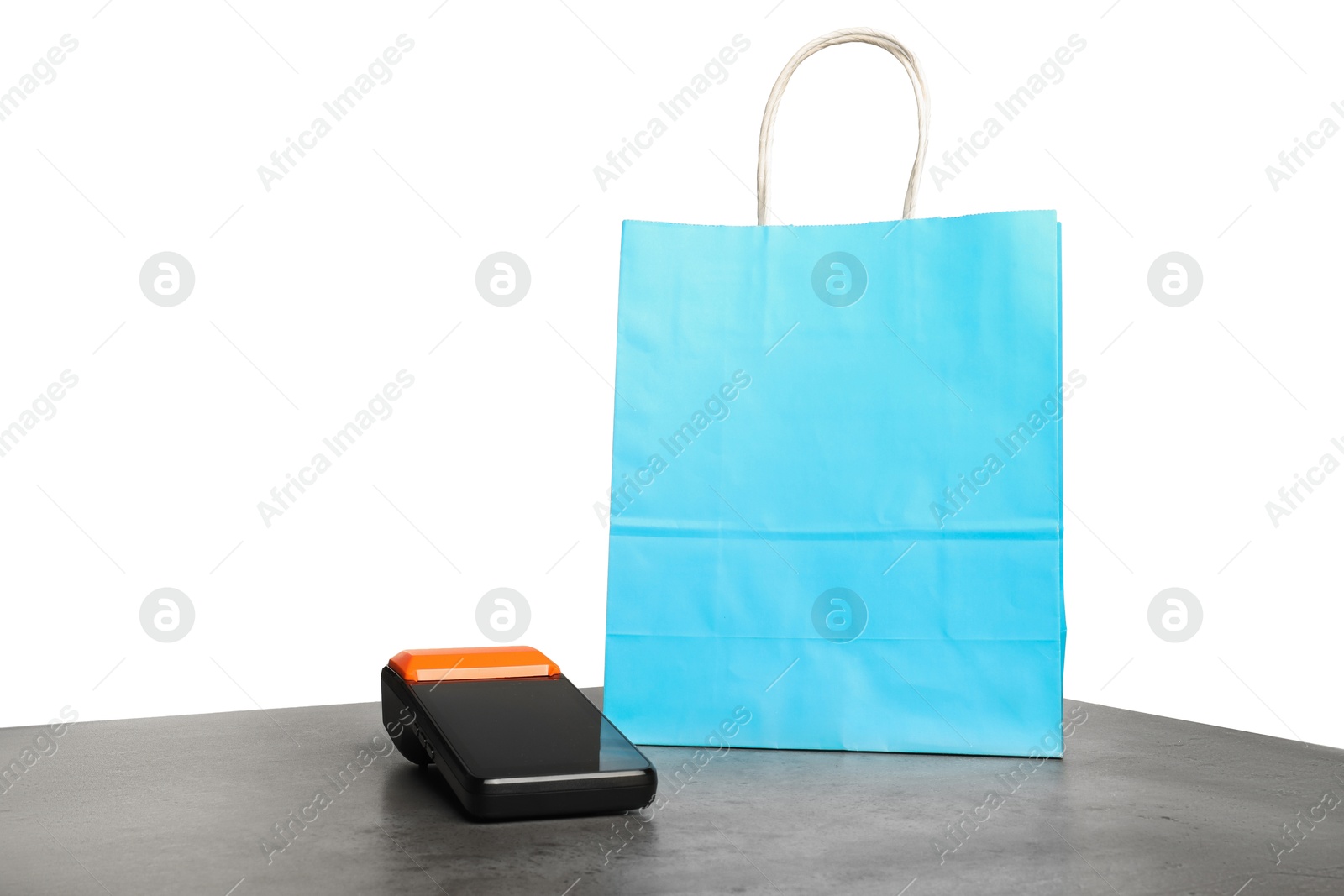 Photo of Payment terminal and shopping bag on grey table against white background