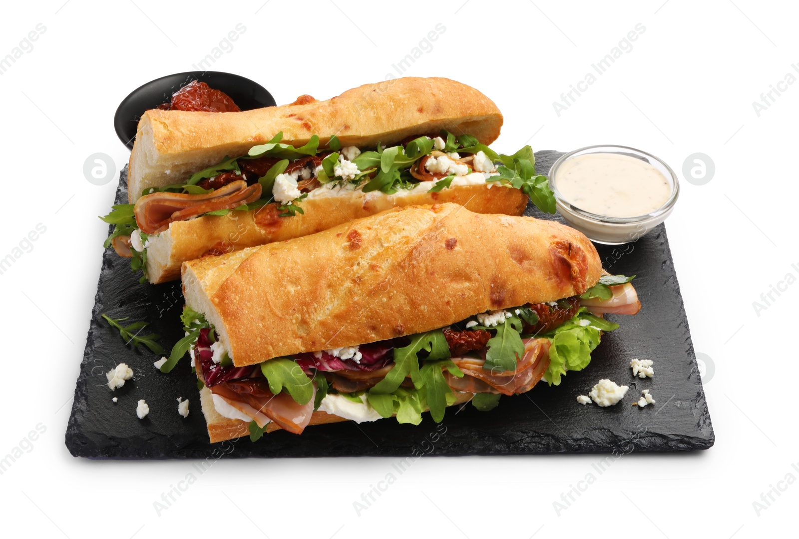 Photo of Halves of baguette sandwich with prosciutto and sun dried tomatoes isolated on white