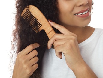 Photo of Woman brushing her curly hair with comb on white background, closeup