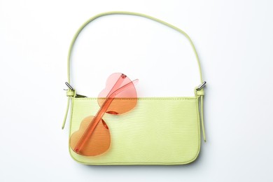 Photo of Baguette bag and heart shaped sunglasses on white background, top view. Stylish accessories