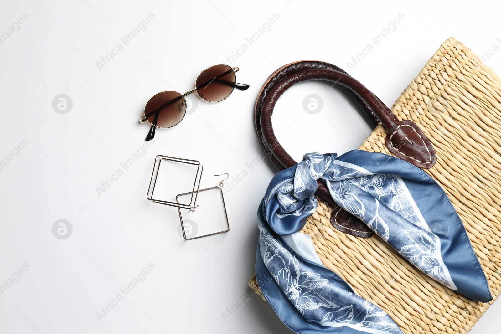 Photo of Wicker bag and stylish accessories on white background, flat lay