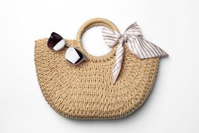 Photo of Wicker bag and sunglasses on white background, top view. Stylish accessories