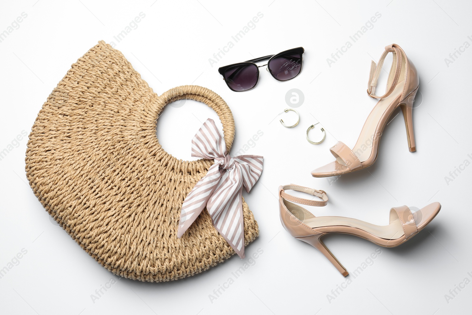 Photo of Wicker bag, heels and stylish accessories on white background, flat lay