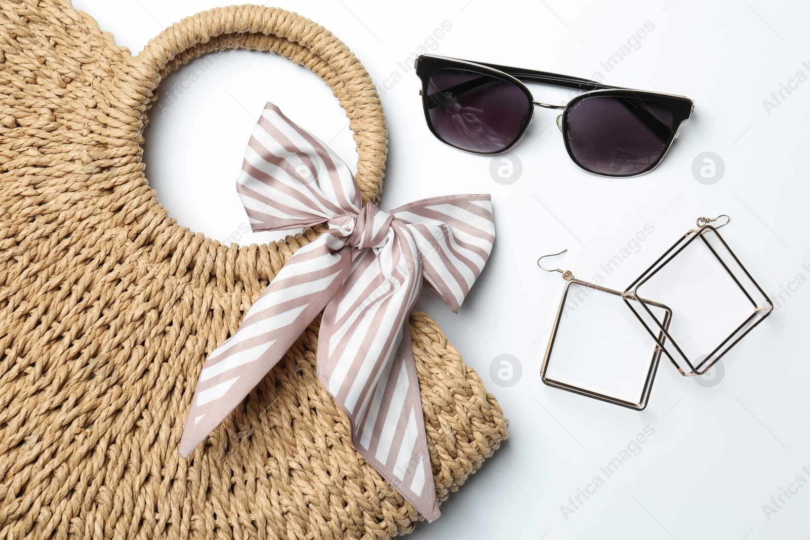 Photo of Wicker bag and stylish accessories on white background, flat lay