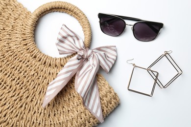 Photo of Wicker bag and stylish accessories on white background, flat lay