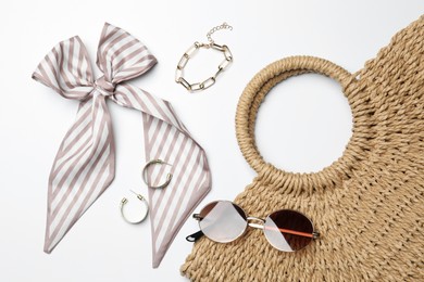 Photo of Wicker bag and stylish accessories on white background, flat lay