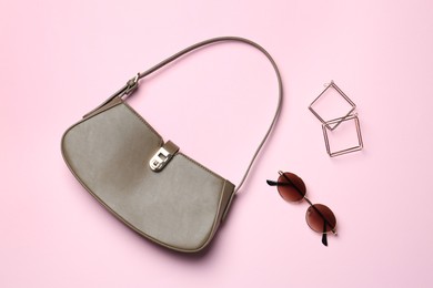 Photo of Beautiful bag and stylish accessories on light pink background, flat lay