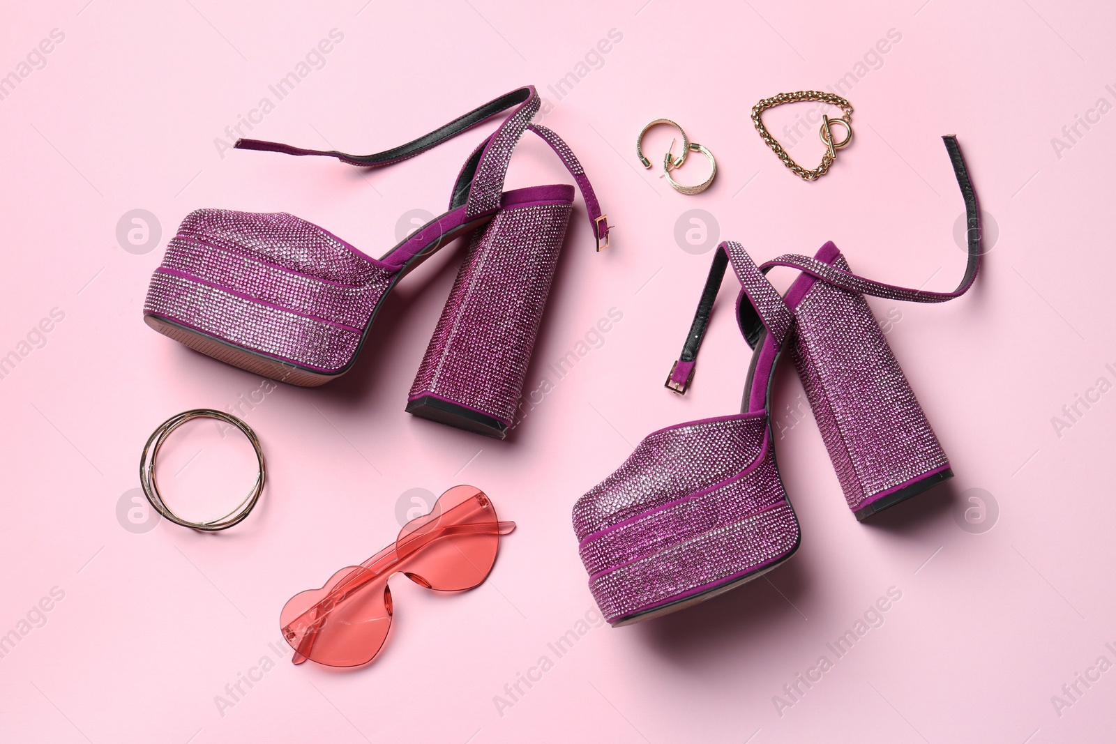 Photo of Stylish accessories and heels on light pink background, flat lay