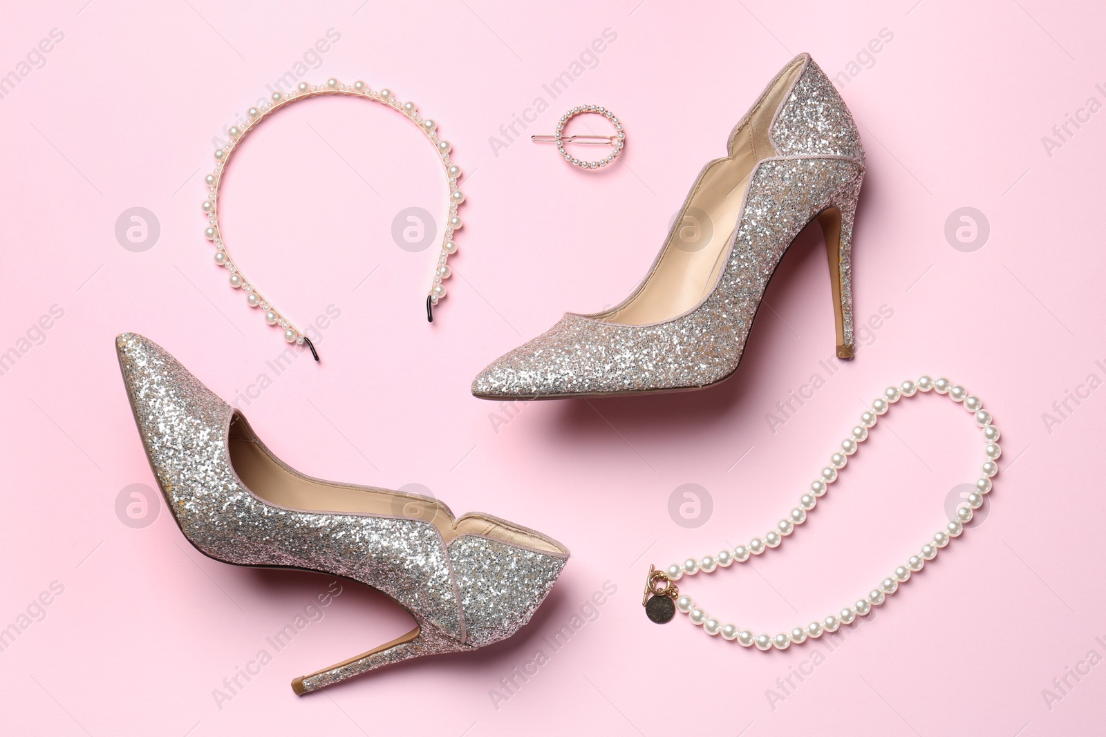 Photo of Stylish accessories and heels on light pink background, flat lay