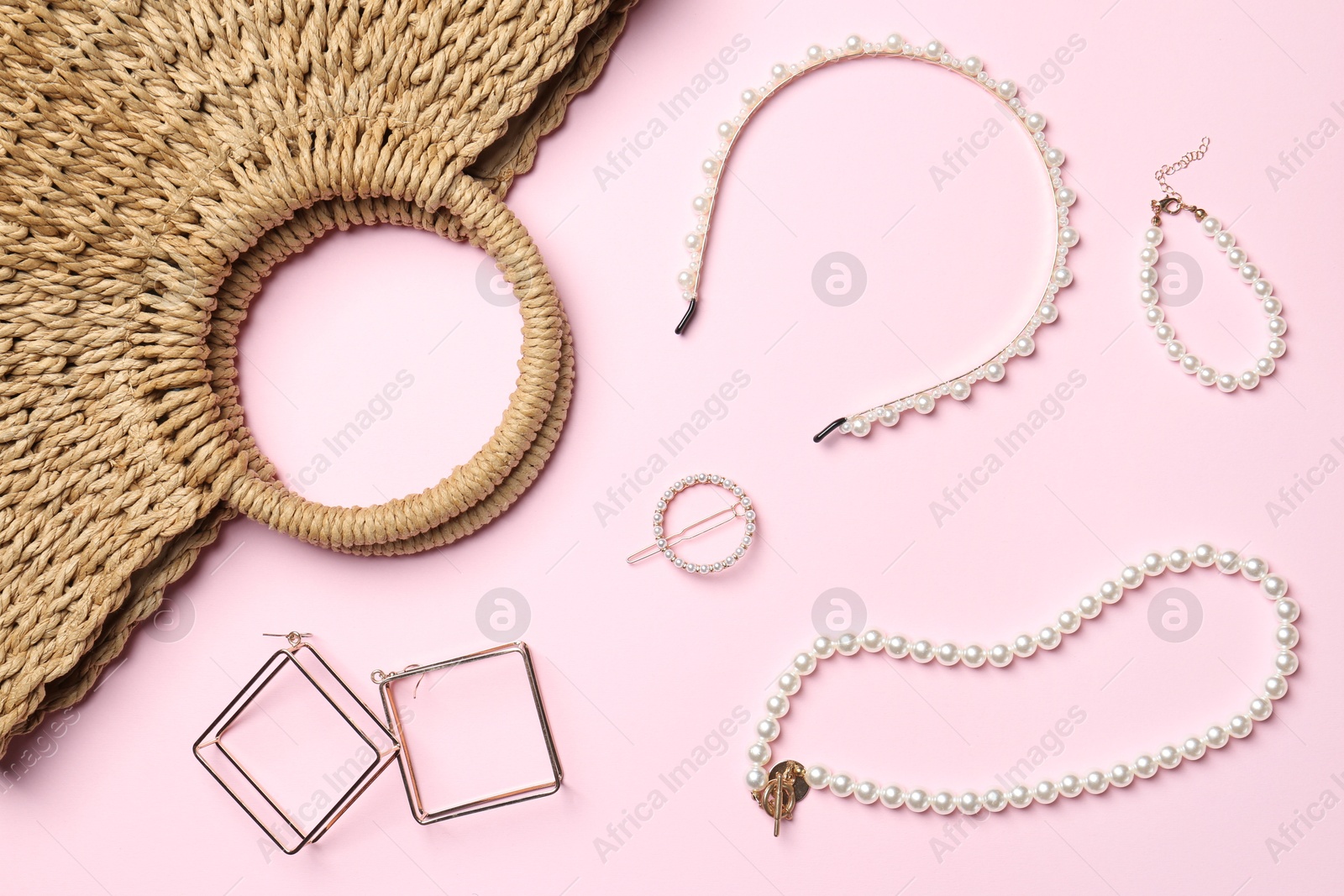 Photo of Wicker bag and stylish accessories on light pink background, flat lay