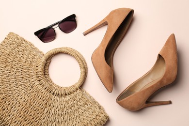 Photo of Wicker bag, shoes and sunglasses on beige background, flat lay. Stylish accessories