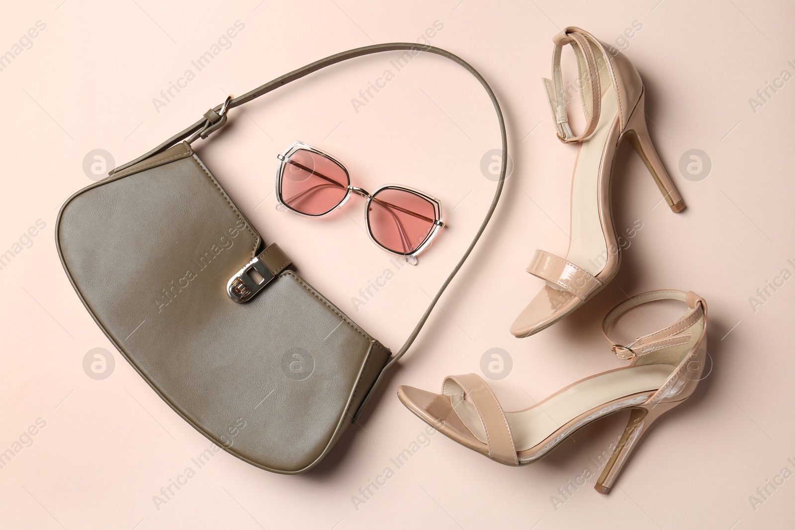 Photo of Baguette bag, heels and sunglasses on beige background, flat lay. Stylish accessories