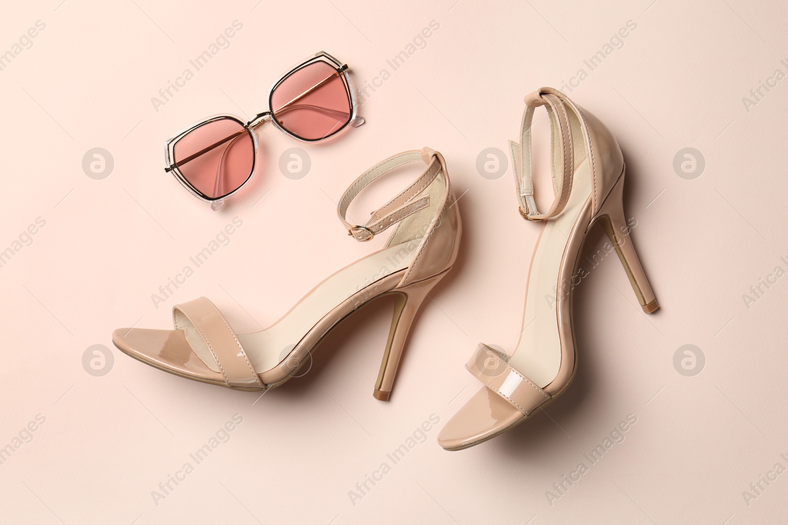 Photo of Shoes and sunglasses on beige background, flat lay. Stylish accessories