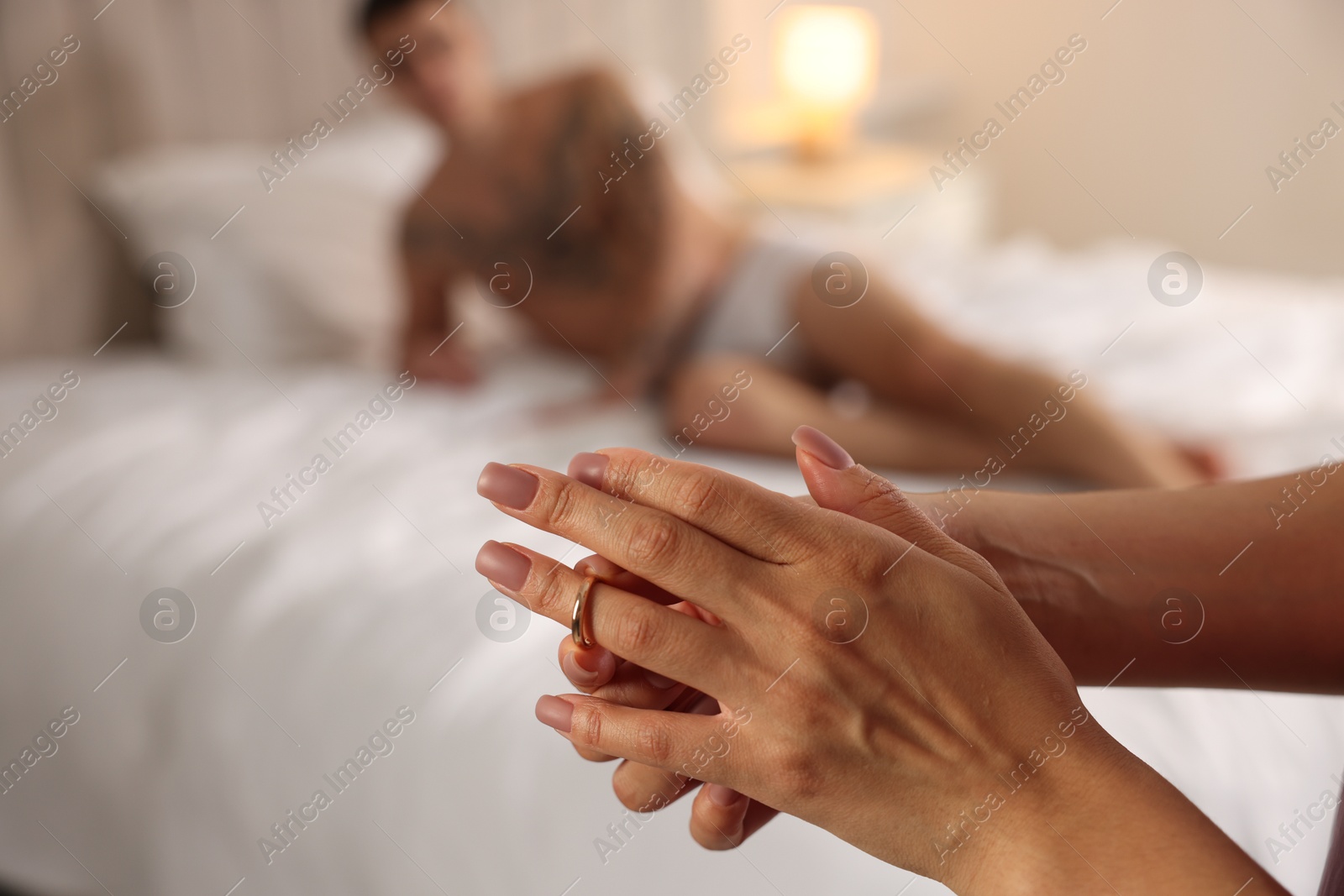 Photo of Betrayal. Unfaithful woman taking off engagement ring before enjoying time together with lover at home, closeup