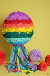 Photo of Colorful pinata and party decor on yellow background