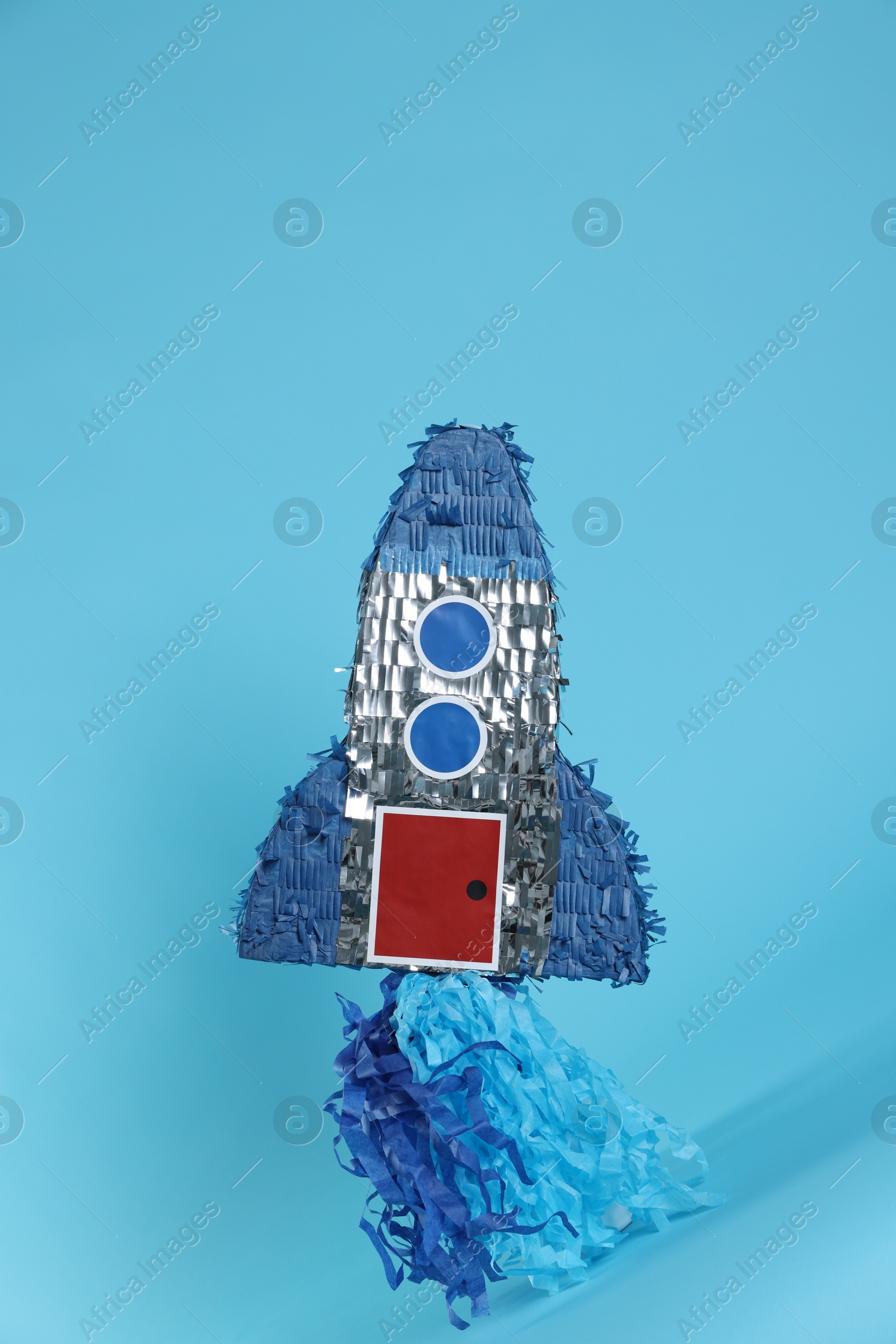 Photo of Rocket shaped pinata on light blue background