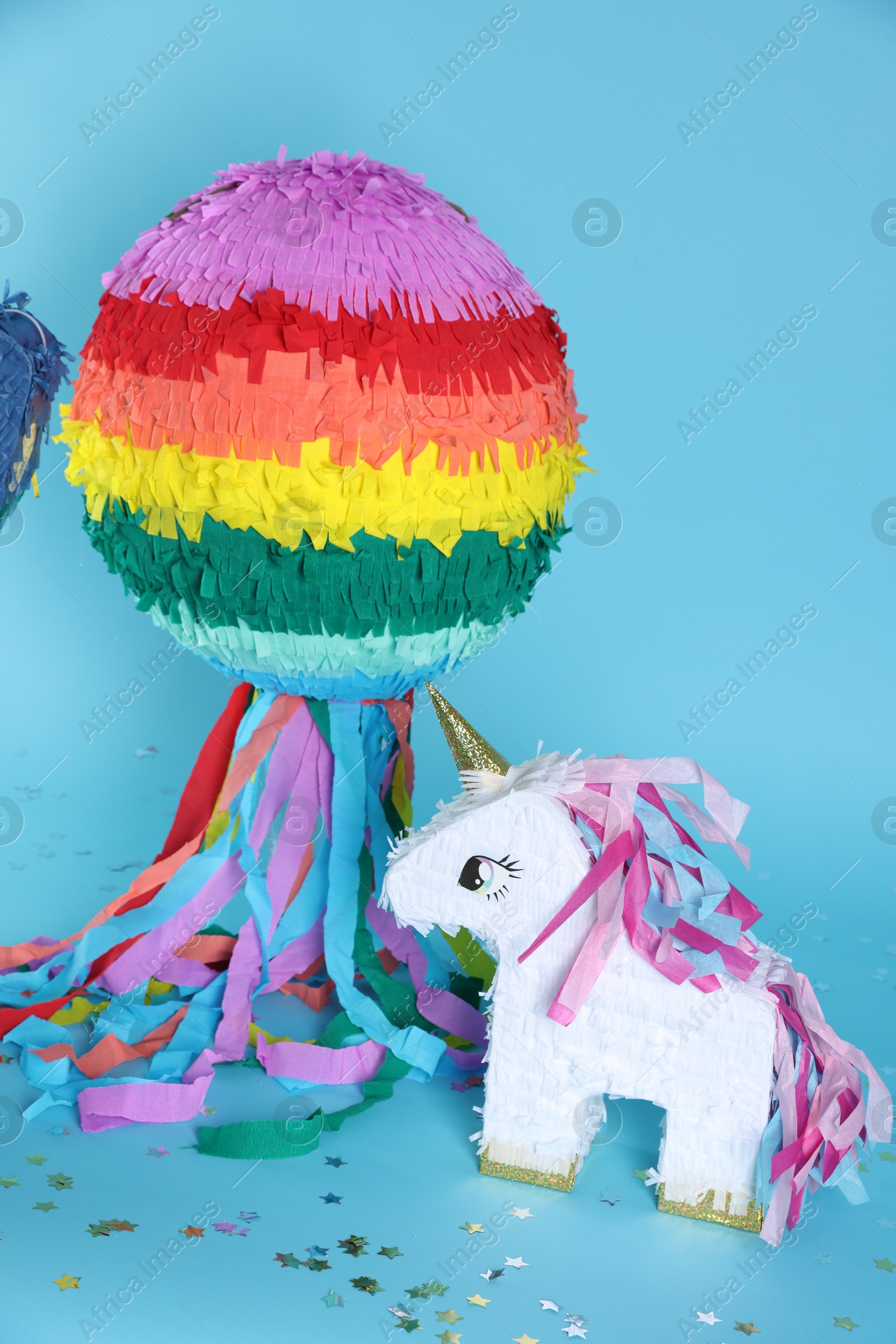 Photo of Bright colorful pinatas and confetti on light blue background