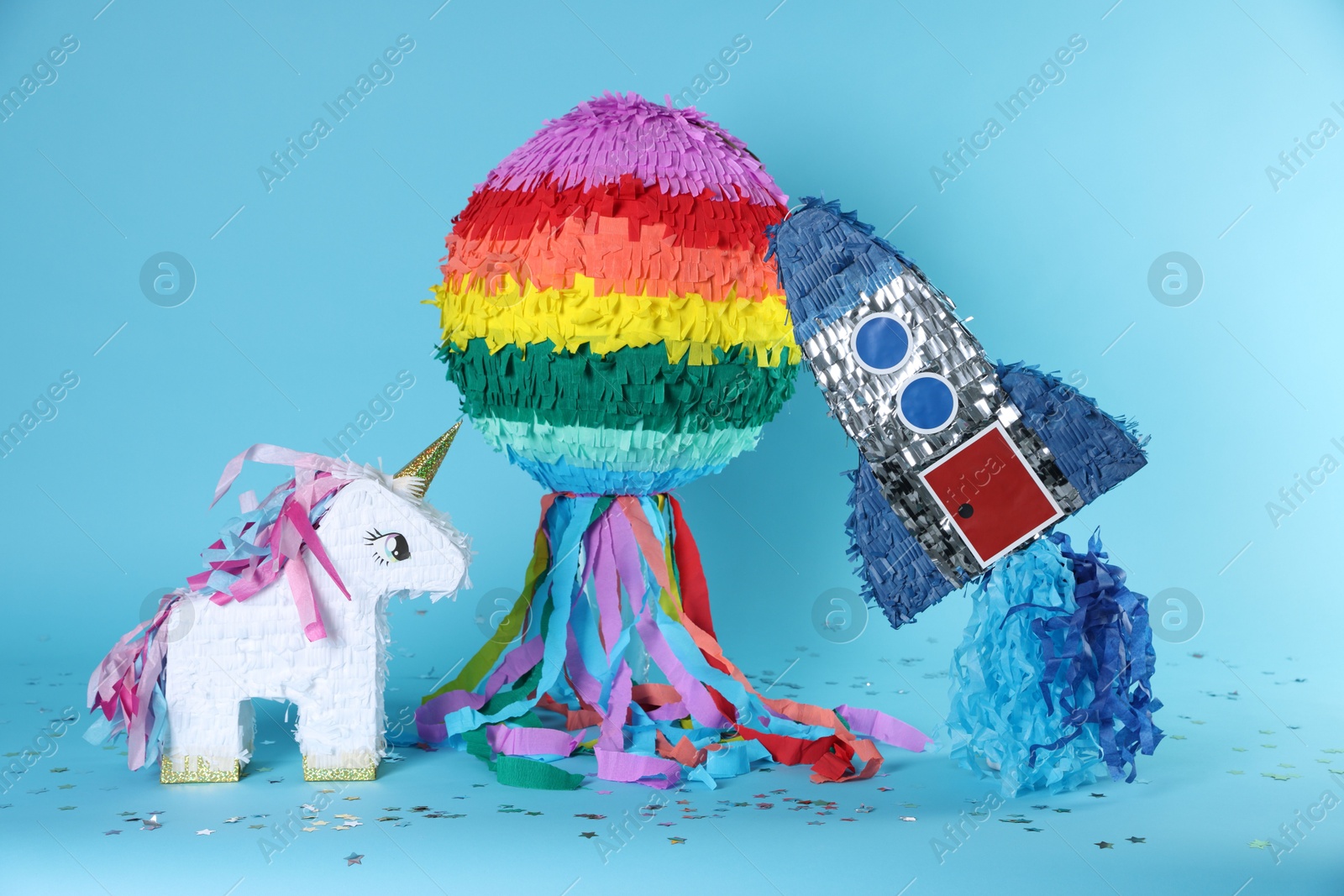 Photo of Different colorful pinatas and confetti on light blue background