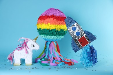 Photo of Different colorful pinatas and confetti on light blue background