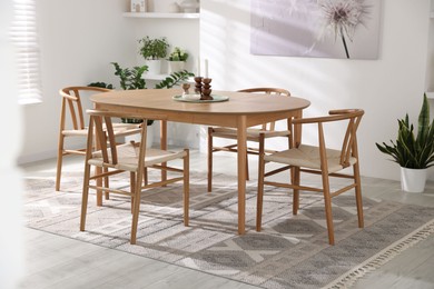 Photo of Stylish room with wooden table, chairs and houseplants. Interior design