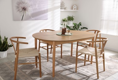 Photo of Stylish room with wooden table, chairs and houseplants. Interior design