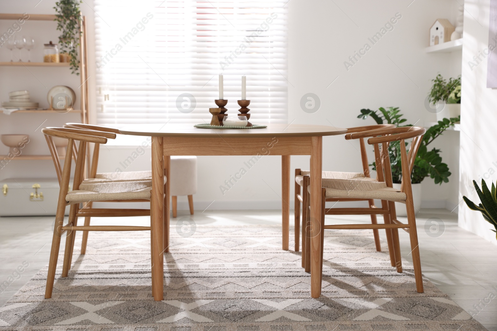 Photo of Stylish room with wooden table, chairs and houseplants. Interior design