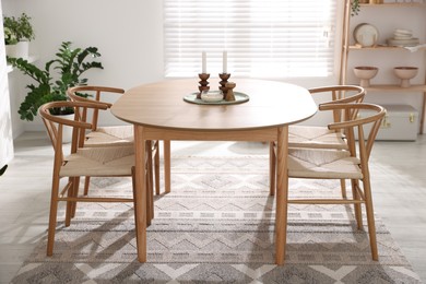 Photo of Stylish room with wooden table, chairs and houseplants. Interior design