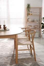 Photo of Wooden table with candles, chairs and houseplants in room