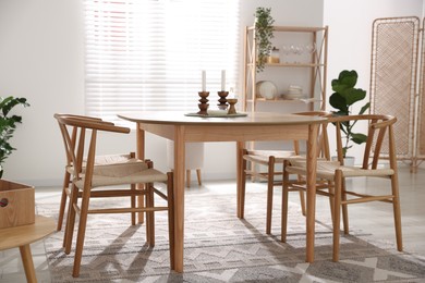 Photo of Stylish room with wooden table, chairs and houseplants. Interior design