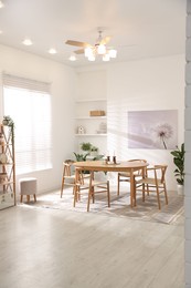 Photo of Stylish room with wooden table, chairs and houseplants. Interior design