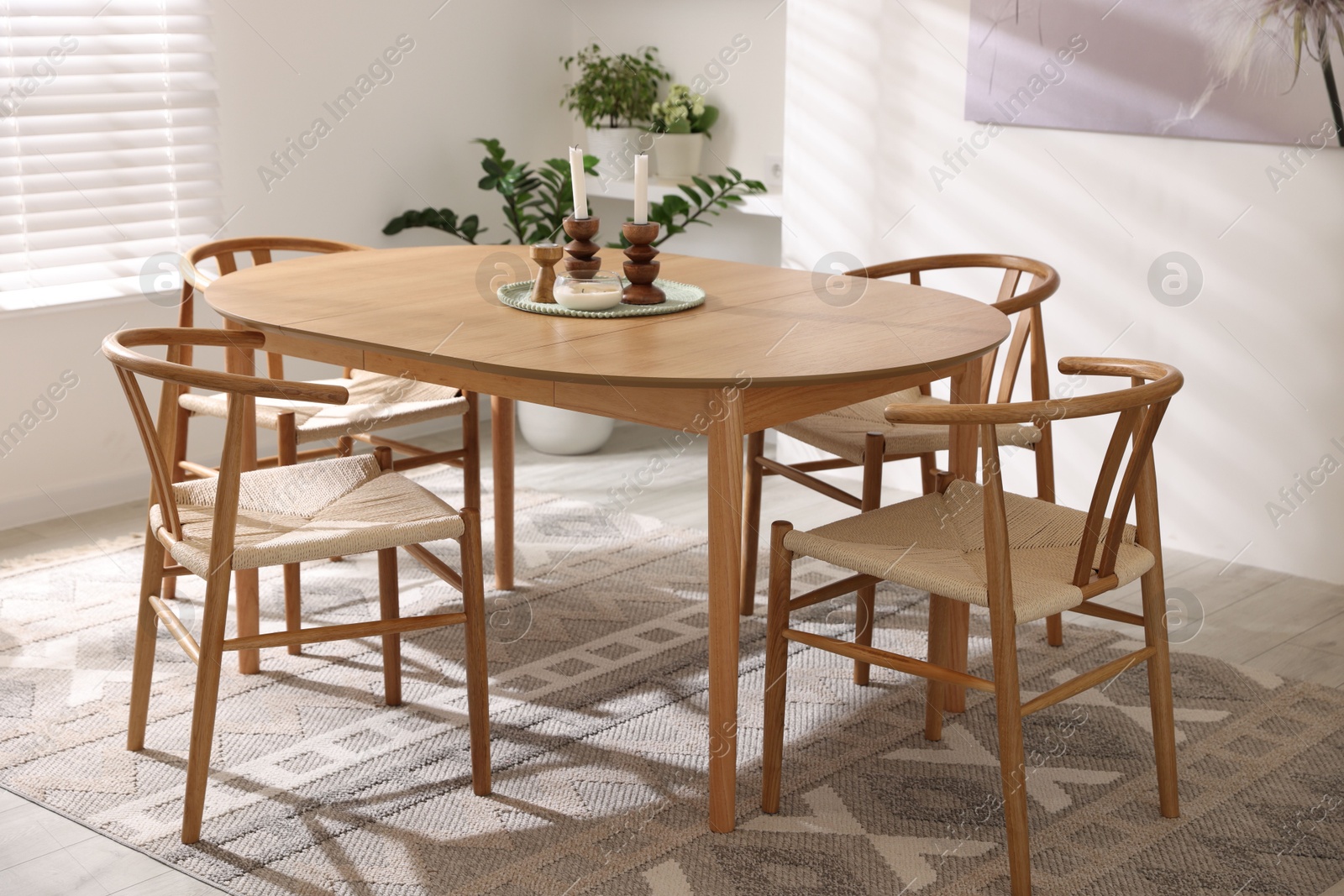 Photo of Stylish room with wooden table, chairs and houseplants. Interior design