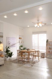 Photo of Stylish room with wooden table, chairs and houseplants. Interior design