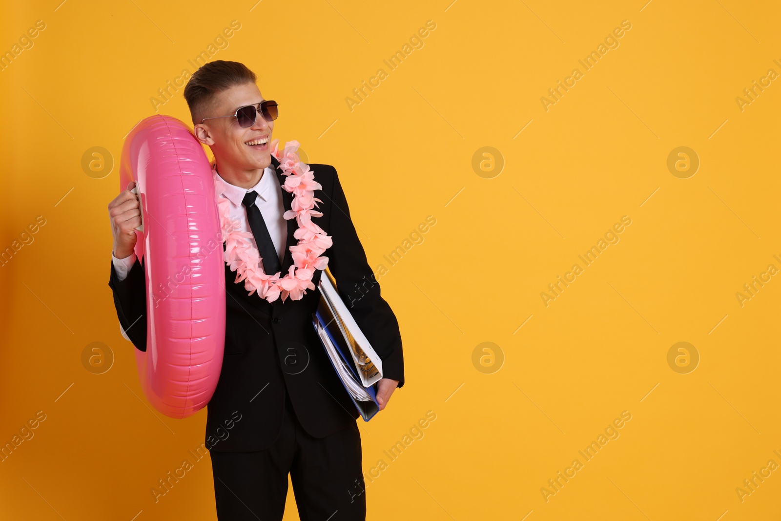 Photo of Businessman with folders, wreath of flowers and inflatable ring on orange background, space for text